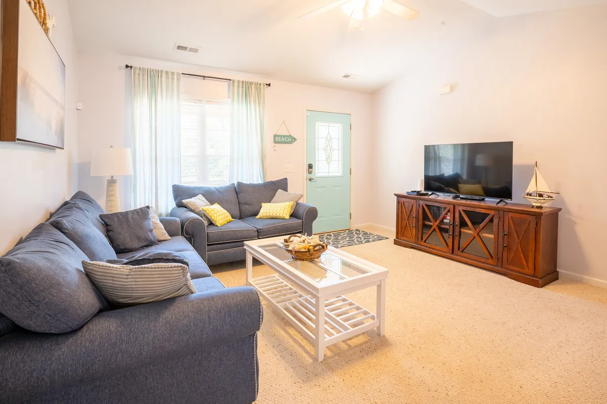 A cozy living room scene featuring sofas arranged around a coffee table, with a television and tasteful decorative items. The room is set up for socializing, whether for movie nights, board games, or casual conversation, making it welcoming for groups and families.