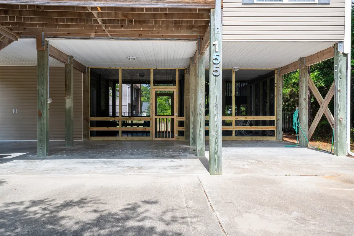 The image shows the exterior of the home, featuring sturdy wooden support beams, a spacious screened porch, and an open area beneath the house. In the scene, the open space is visibly inviting for children to play, while adults can gather in the shaded porch area. There is also room underneath for secure parking and storage of beach or lawn gear.