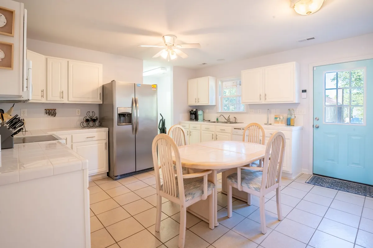 A welcoming kitchen and dining setting with a dining table, kitchen island, refrigerator, and sunny window. The layout makes it easy for groups to cook, chat, and dine together, matching the section's emphasis on group gatherings and family-friendly design.